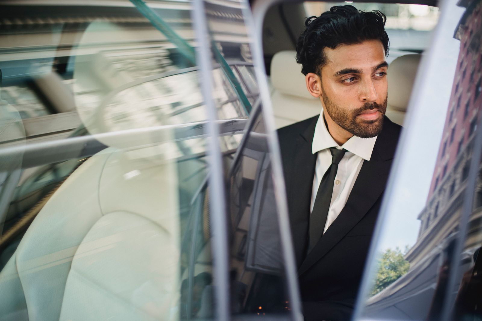 An executive in a suit seated in the back of a car