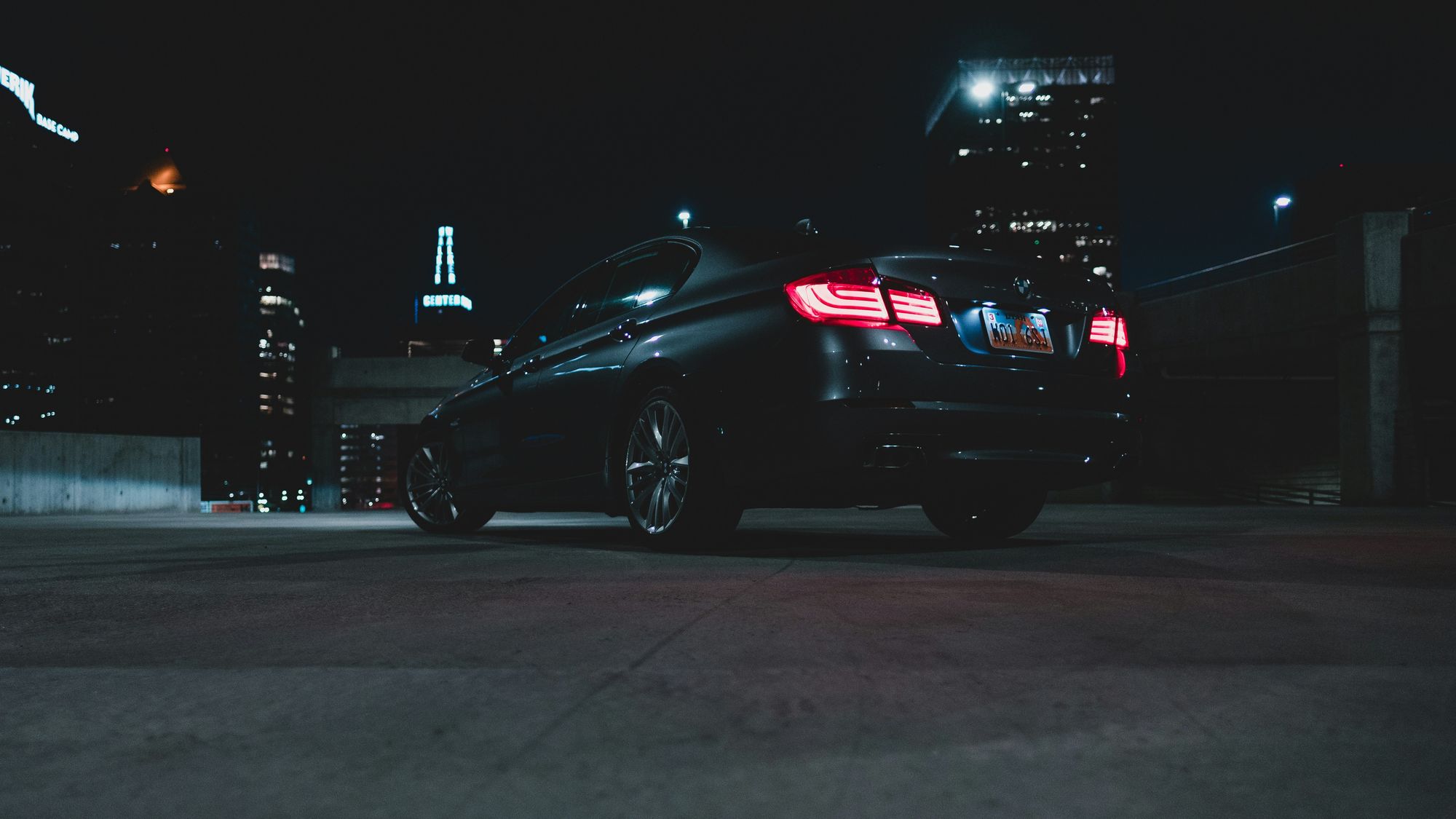 A black luxury sedan waiting under city lights at night