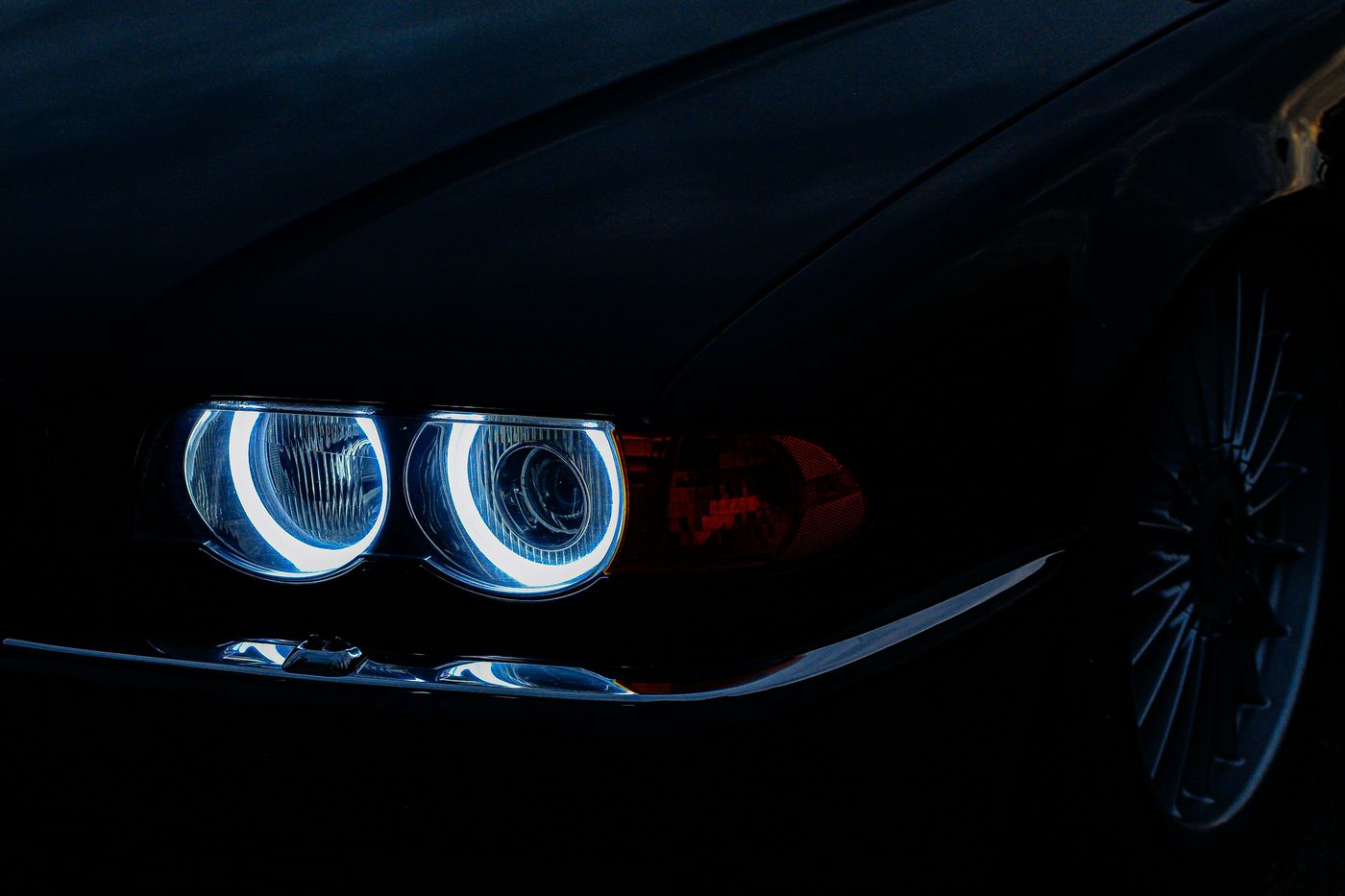 The lit headlight of a black car at night
